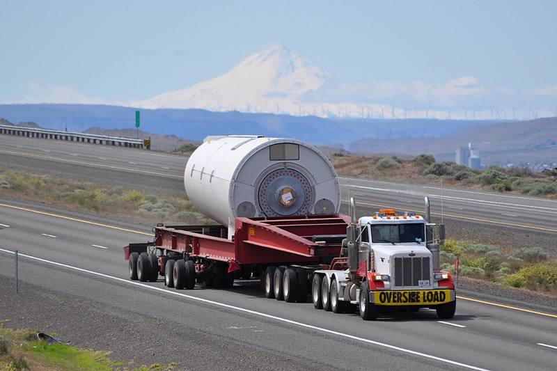 A truck carrying an oversize load with a banner